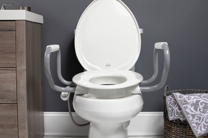 E/R85320H20 ARM Bemis Independence Assurance® with Clean·Shield™, Support Arms, and Personal Wash Bidet is a Plastic 3" Raised Toilet Seat Featuring Stay·Tite® Commercial Fastening System™ and Super·Grip® Bumpers